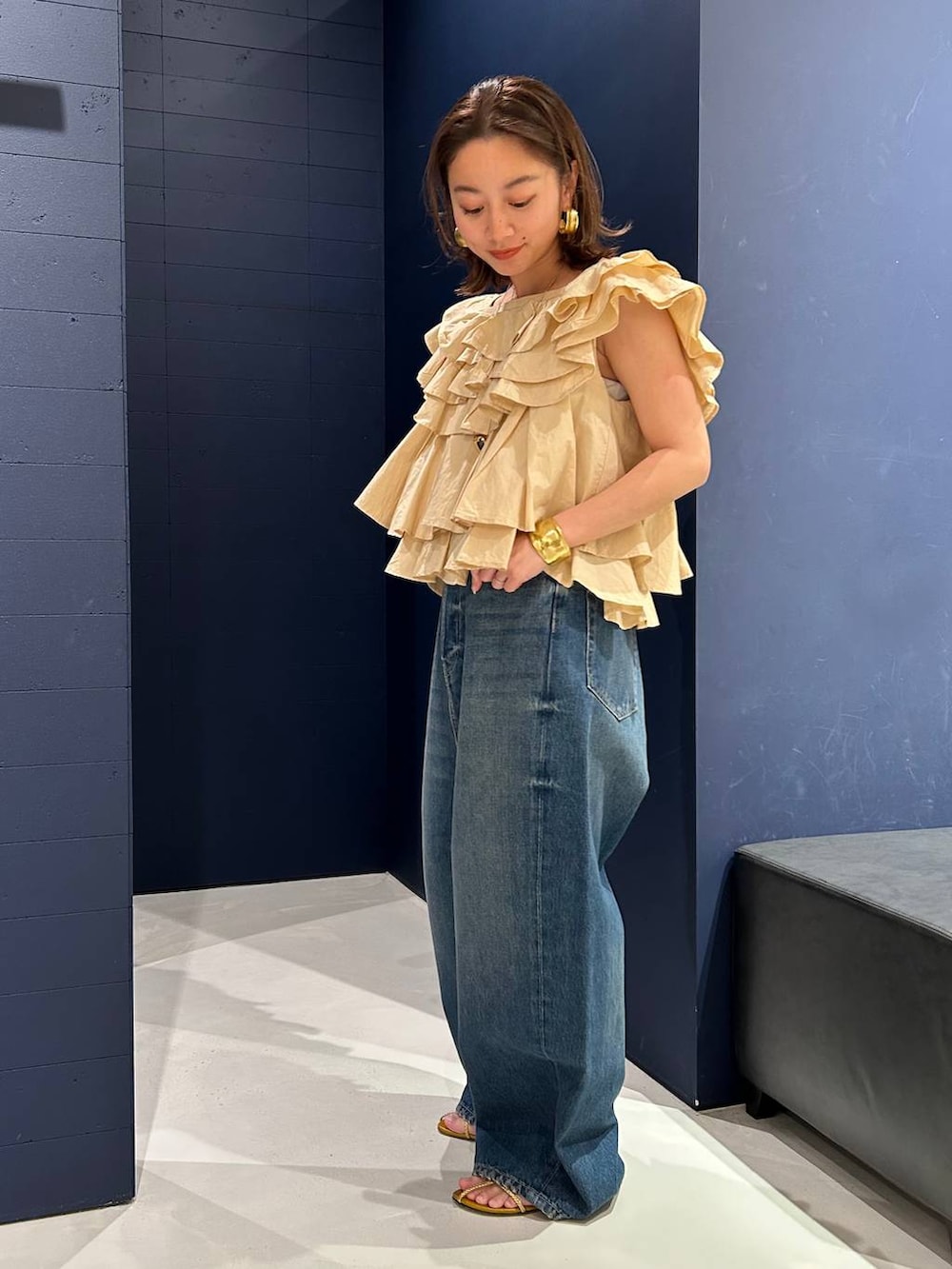 ブルー系のデニムパンツ、ベージュ系のシャツ/ブラウス、ゴールド系のバングル/リストバンドを着用したレディースの春コーディネートの5枚目の写真