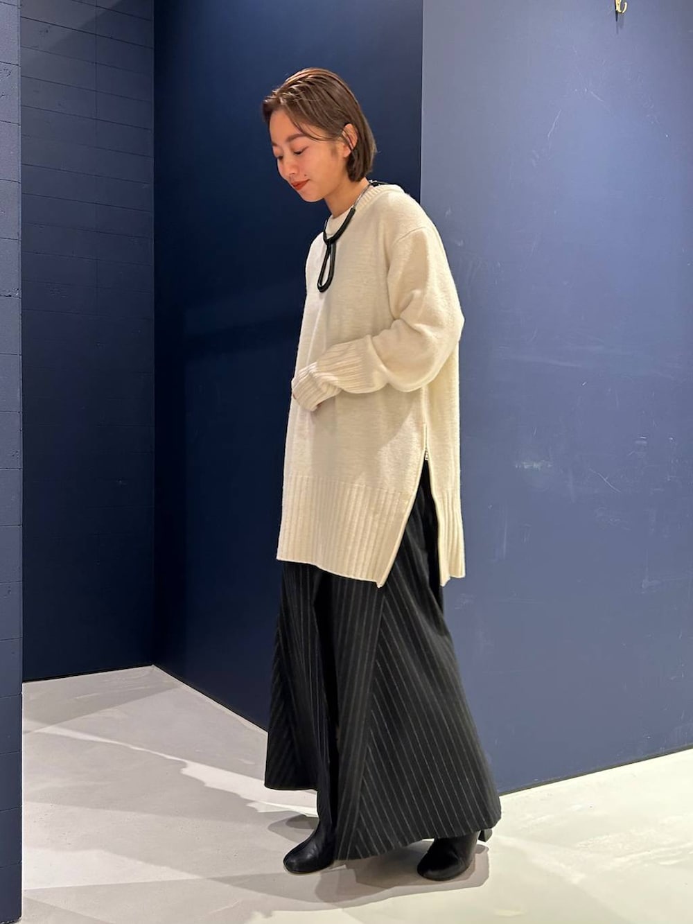 ホワイト系のニット/セーター、グレー系のスカートを着用したレディースの冬コーディネートの2枚目の写真