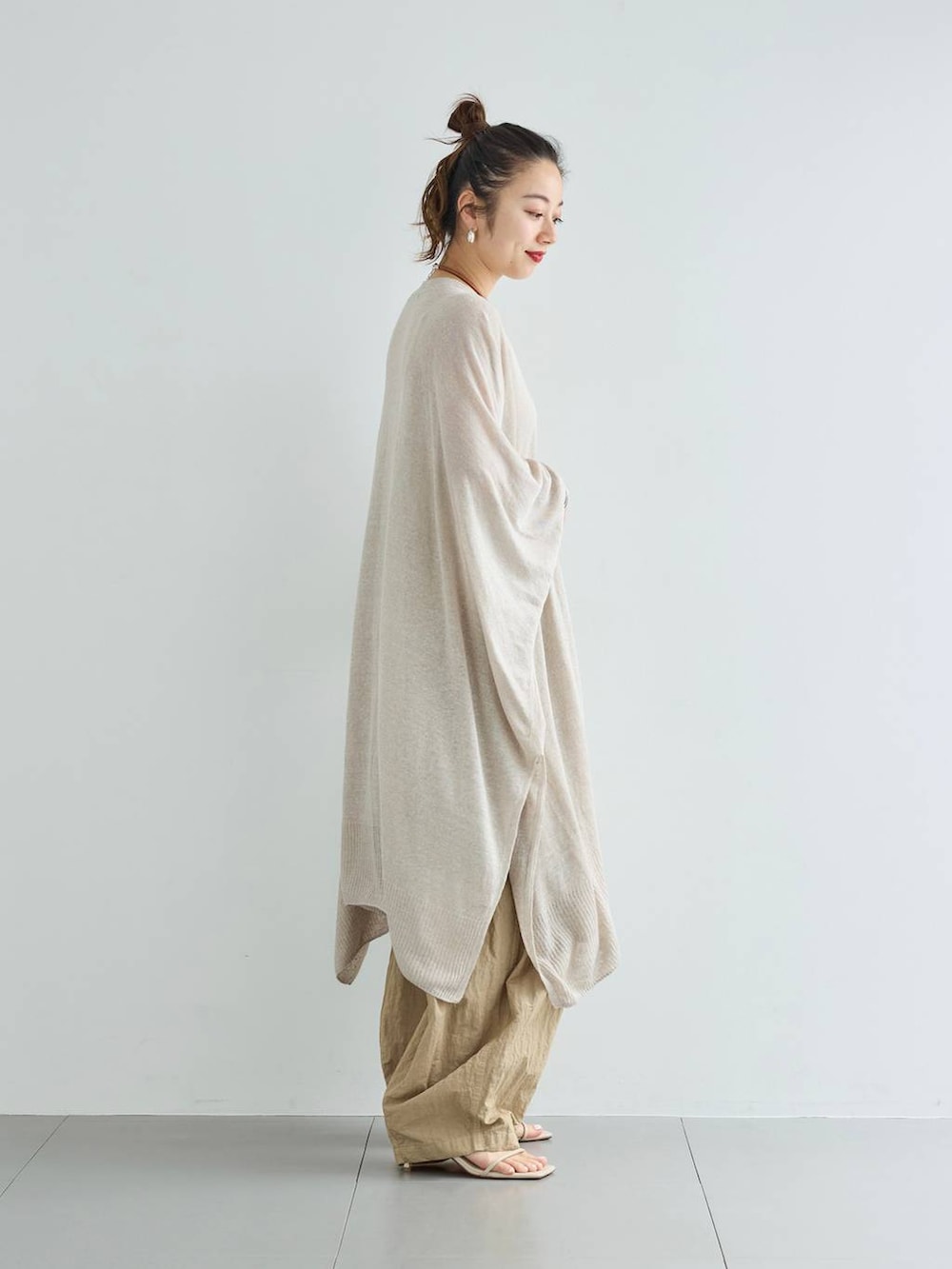 ベージュ系のその他パンツ、グレー系のニット/セーター、シルバー系のピアス(両耳用)を着用したレディースの夏コーディネートの2枚目の写真