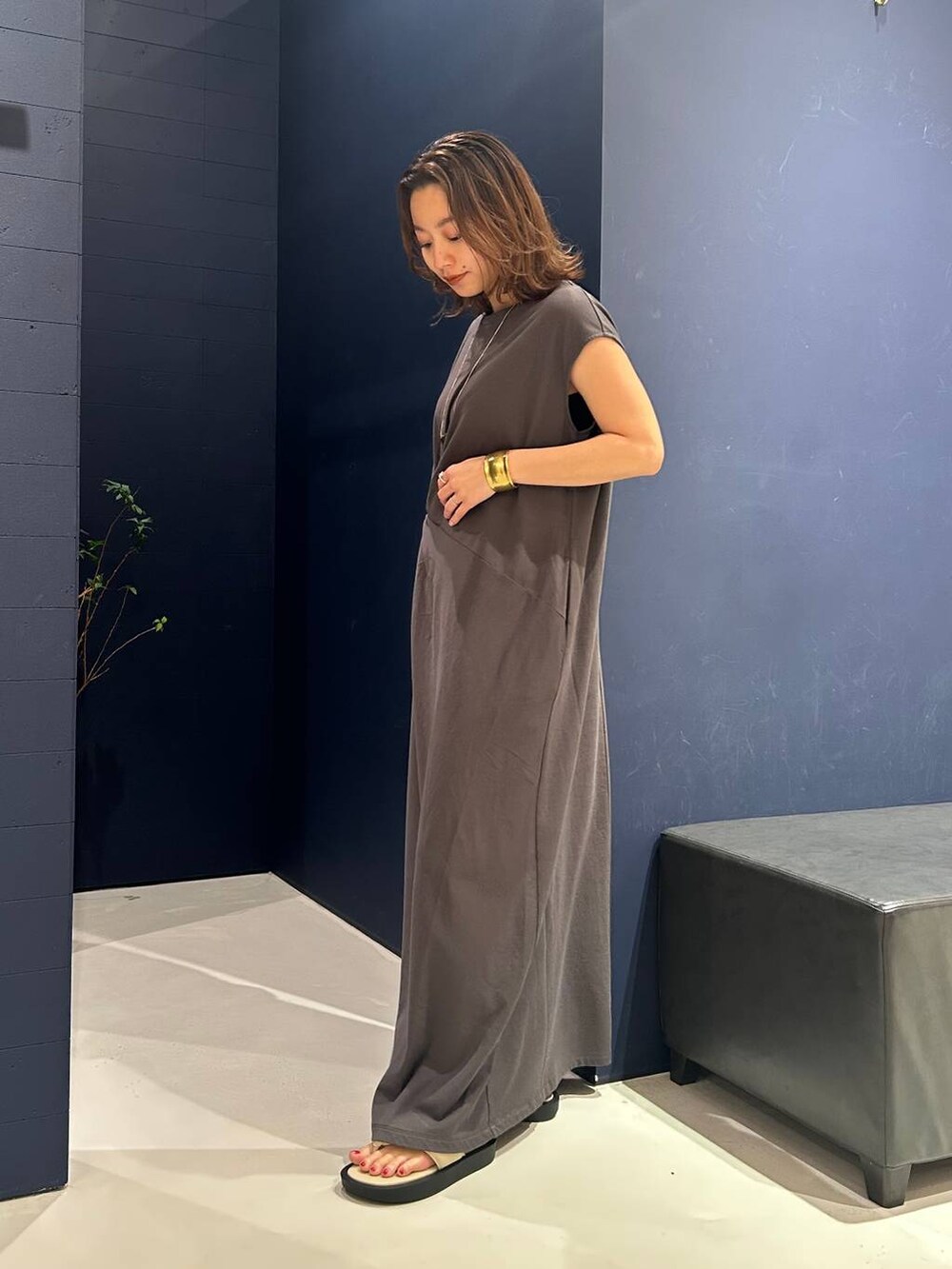 グレー系のワンピース、ゴールド系のバングル/リストバンド、ゴールド系のネックレスを着用したレディースの夏コーディネートの2枚目の写真