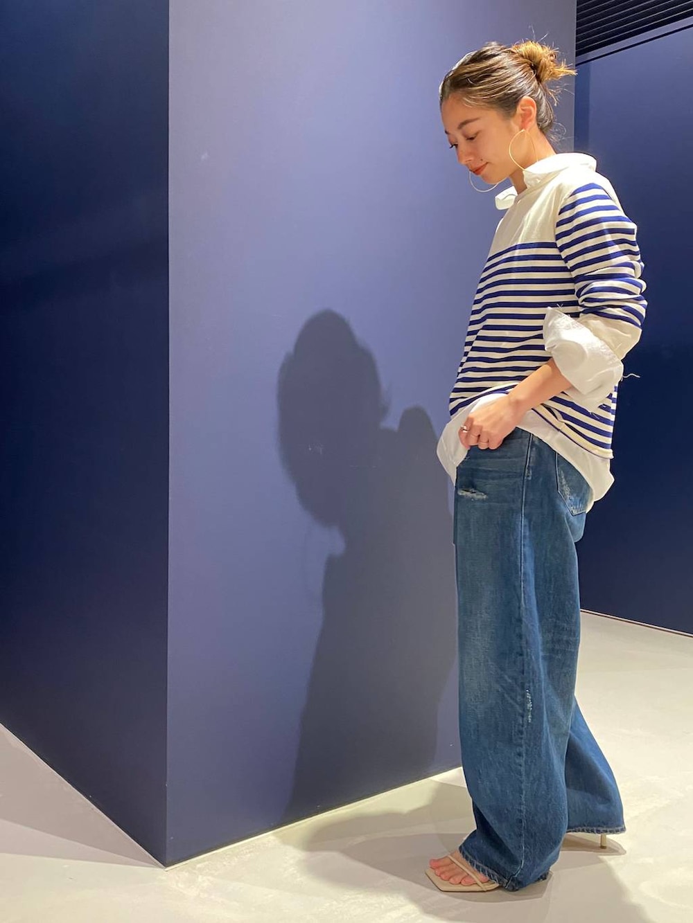 ブルー系のデニムパンツ、ホワイト系のシャツ/ブラウス、ホワイト系のニット/セーターを着用したレディースの夏コーディネートの3枚目の写真