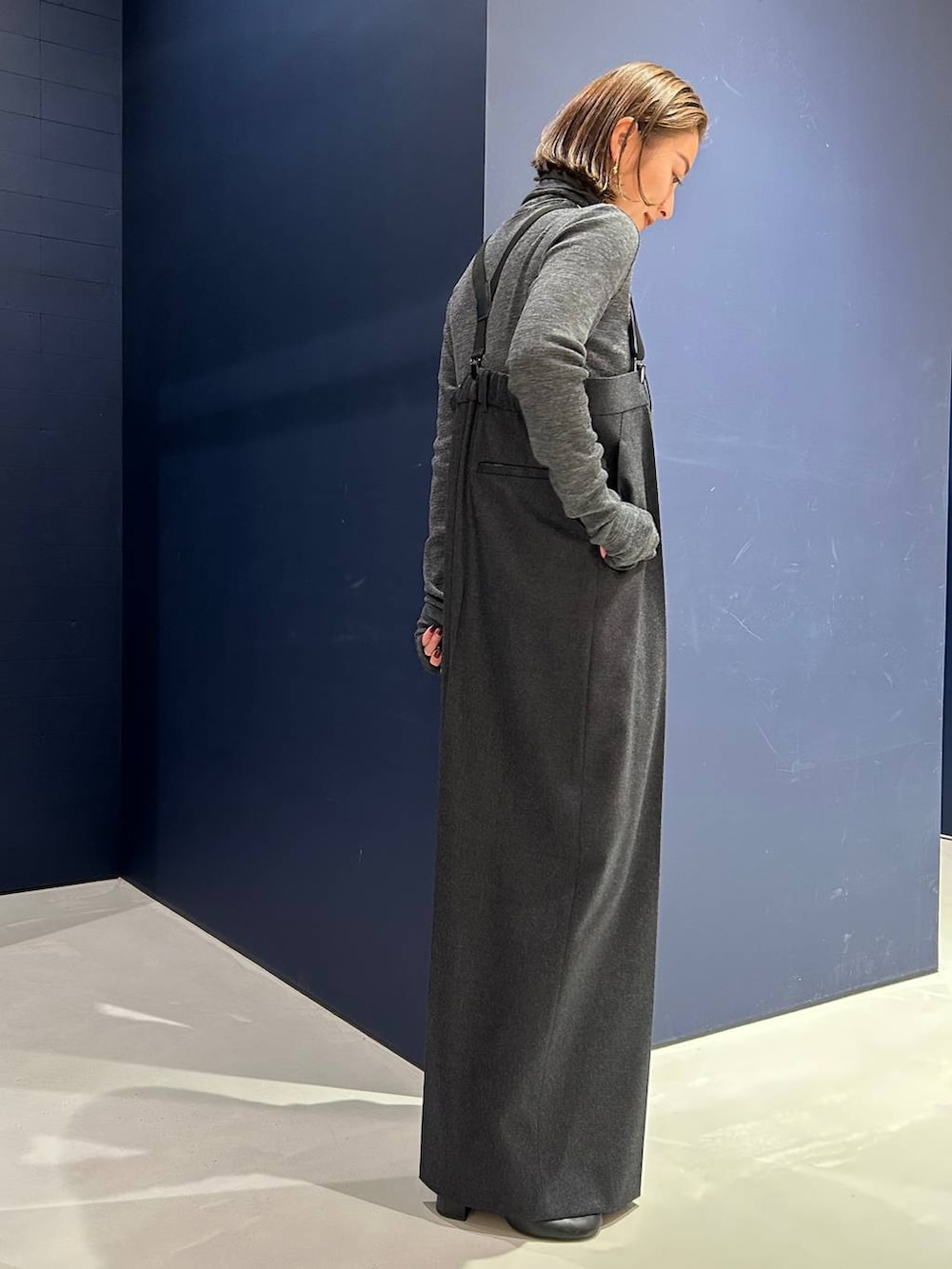 グレー系のサロペット/オーバーオール、グレー系のニット/セーター、ゴールド系のチョーカーを着用したレディースの冬コーディネートの3枚目の写真