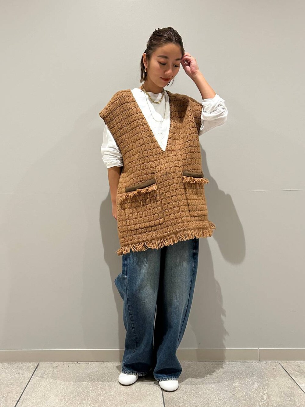 ブルー系のデニムパンツ、ホワイト系のTシャツ/カットソー、イエロー系のベストを着用したレディースの秋コーディネートの2枚目の写真