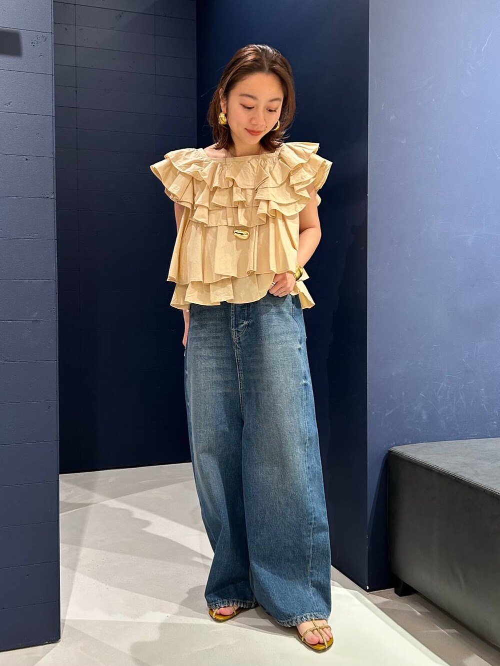 ブルー系のデニムパンツ、ベージュ系のシャツ/ブラウス、ゴールド系のバングル/リストバンドを着用したレディースの春コーディネートの4枚目の写真