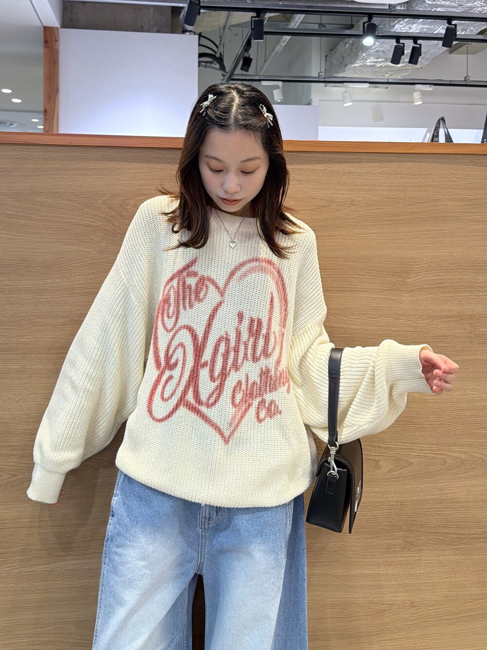 ブルー系のデニムパンツ、ブラック系のショルダーバッグ、ベージュ系のステンカラーコートを着用したレディースの冬コーディネートの2枚目の写真