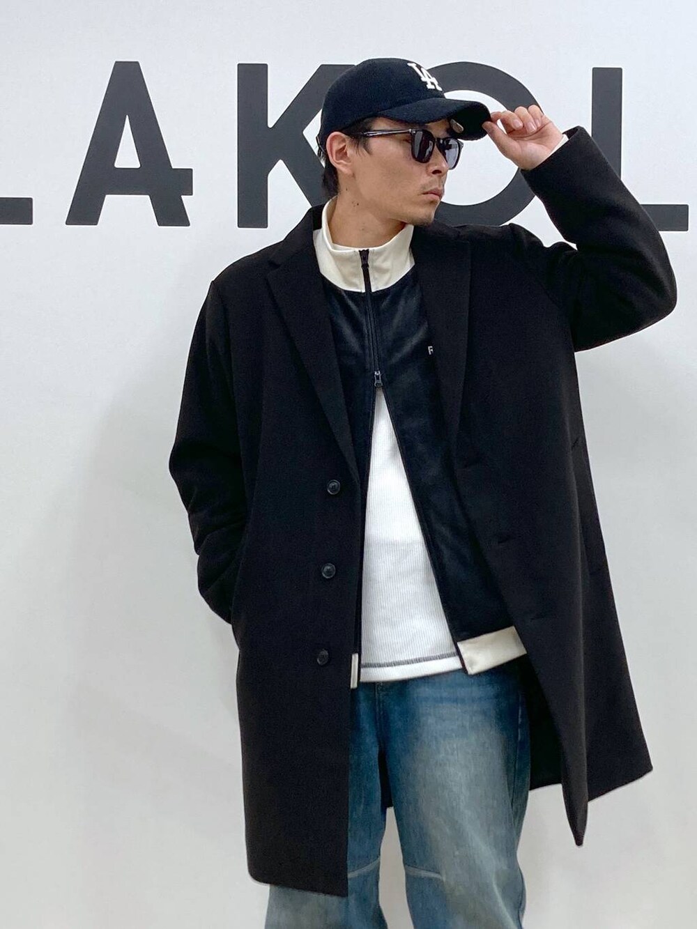 ブラック系のチェスターコート、ブルー系のデニムパンツ、ホワイト系のTシャツ/カットソーを着用したメンズの秋コーディネートの8枚目の写真