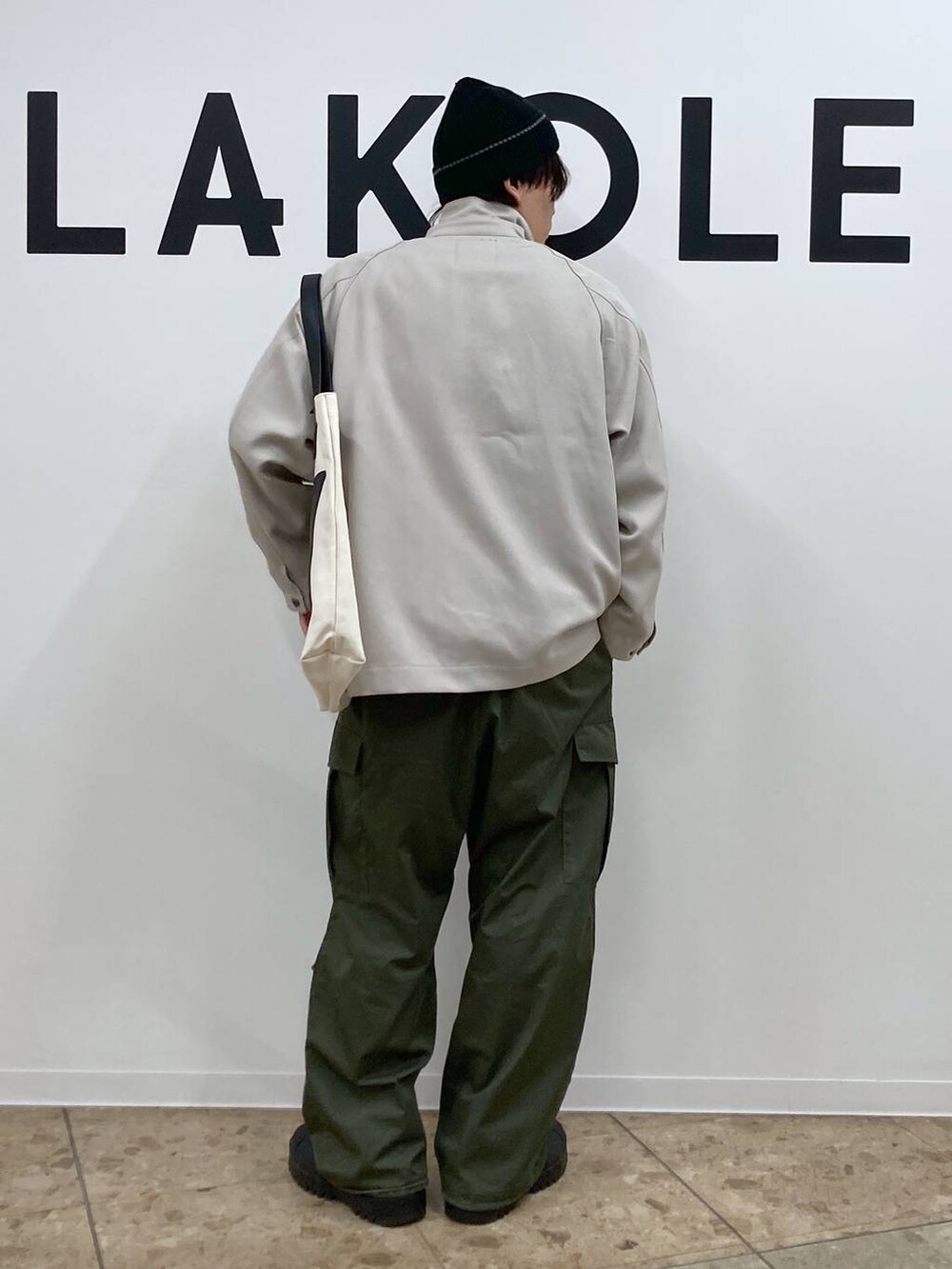 ベージュ系のトートバッグ、ブラック系のその他トップス、グリーン系のカーゴパンツを着用したメンズの冬コーディネートの2枚目の写真