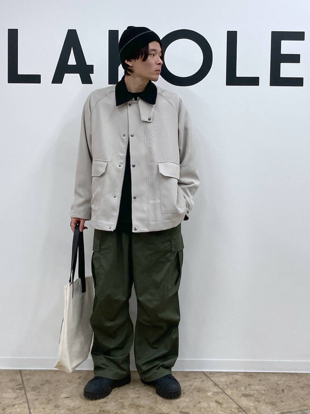 ベージュ系のトートバッグ、ブラック系のその他トップス、グリーン系のカーゴパンツを着用したメンズの冬コーディネートの7枚目の写真