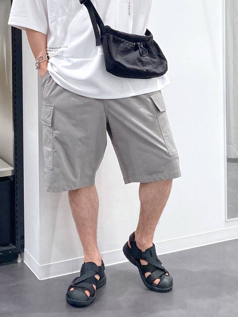 ブラック系のサンダル、ホワイト系のTシャツ/カットソー、ブラック系のショルダーバッグを着用したメンズの夏コーディネートの6枚目の写真