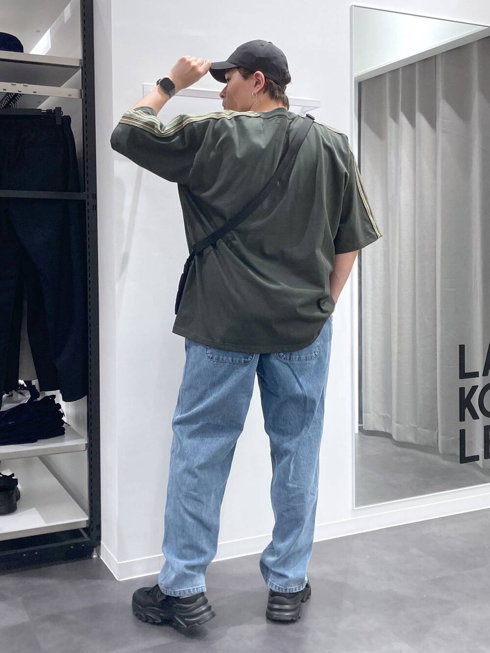 ブラック系のスニーカー、ブラック系のショルダーバッグ、ブルー系のデニムパンツを着用したメンズの夏コーディネートの2枚目の写真