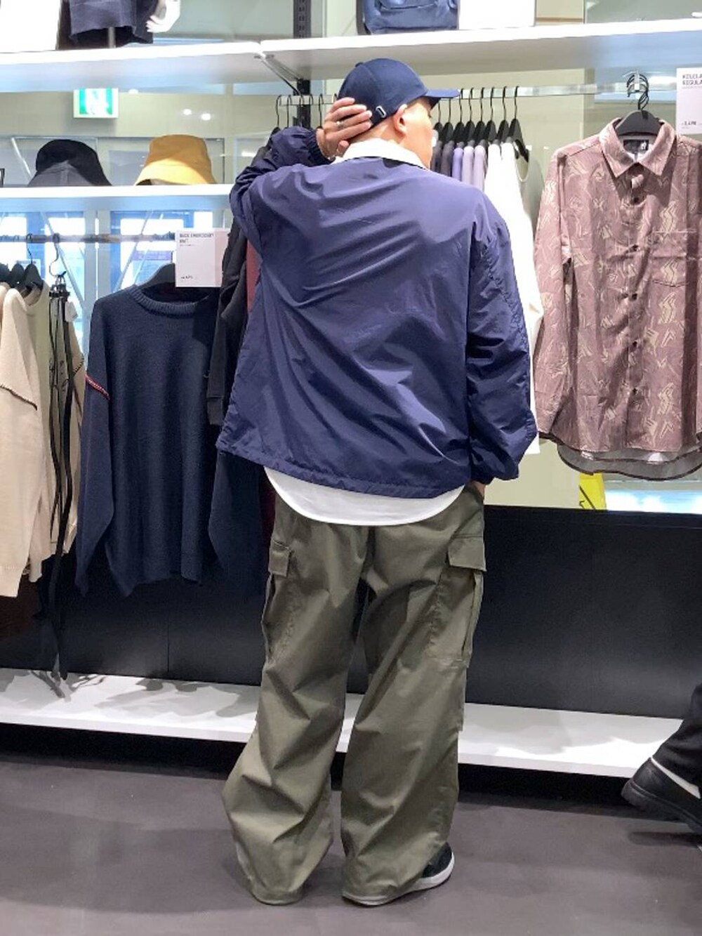 ブラック系のスニーカー、グリーン系のカーゴパンツ、ブルー系のキャップを着用したメンズの秋コーディネートの2枚目の写真