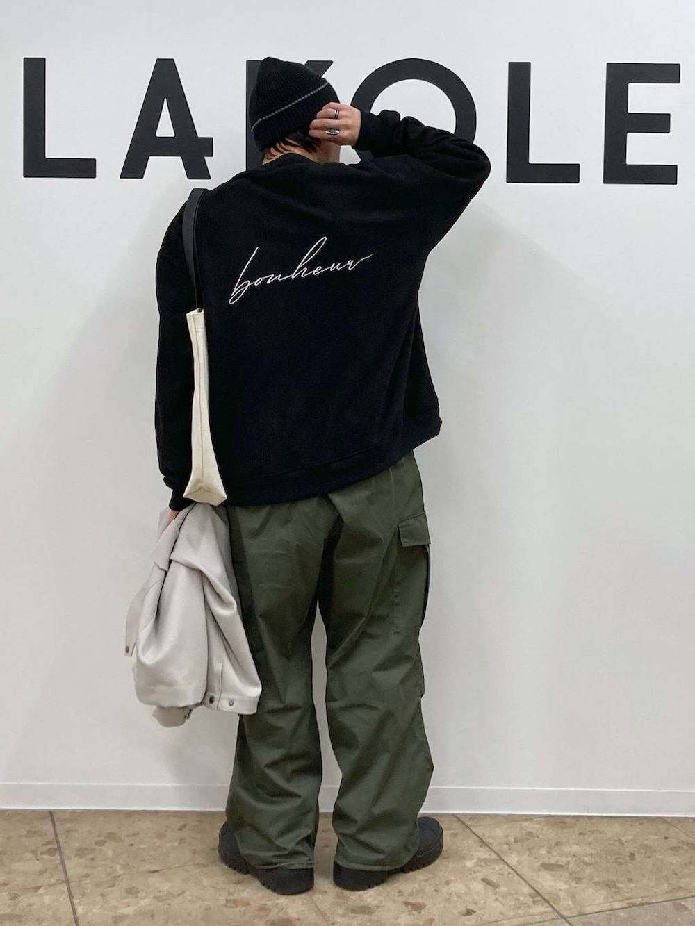 ベージュ系のトートバッグ、ブラック系のその他トップス、グリーン系のカーゴパンツを着用したメンズの冬コーディネートの6枚目の写真