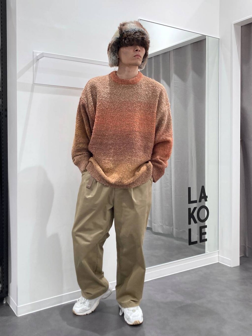 ホワイト系のスニーカー、オレンジ系のニット/セーター、ベージュ系のチノパンツを着用したメンズの秋コーディネートの8枚目の写真