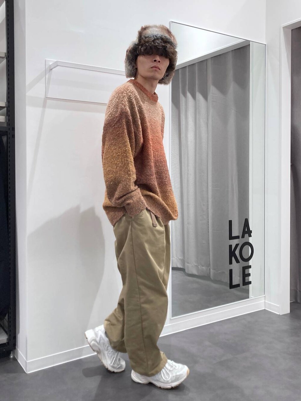 ホワイト系のスニーカー、オレンジ系のニット/セーター、ベージュ系のチノパンツを着用したメンズの秋コーディネートの4枚目の写真