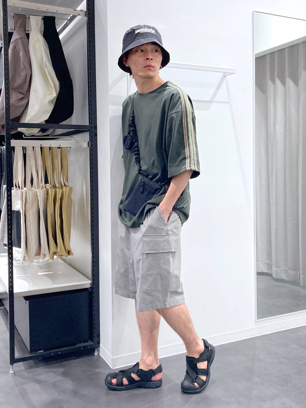 ブラック系のショルダーバッグ、ブラック系のサンダル、グリーン系のTシャツ/カットソーを着用したメンズの夏コーディネートの3枚目の写真