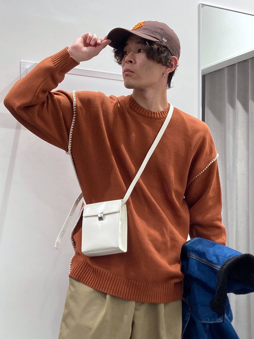 ブルー系のデニムジャケット、ベージュ系のチノパンツ、オレンジ系のニット/セーターを着用したメンズの冬コーディネートの9枚目の写真