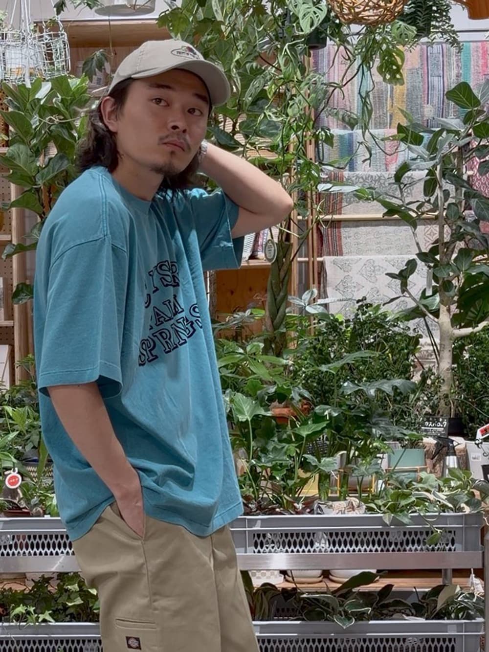 グリーン系のTシャツ/カットソー、ブルー系のスポーツグッズ、ベージュ系のキャップを着用したメンズの夏コーディネートの7枚目の写真