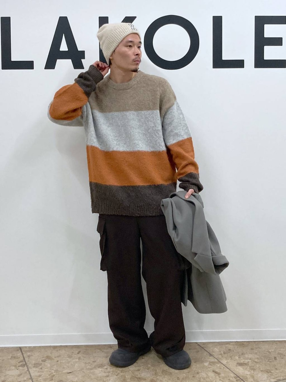 グレー系のチェスターコート、ブラウン系のカーゴパンツ、ブラウン系のニット/セーターを着用したメンズの冬コーディネートの5枚目の写真