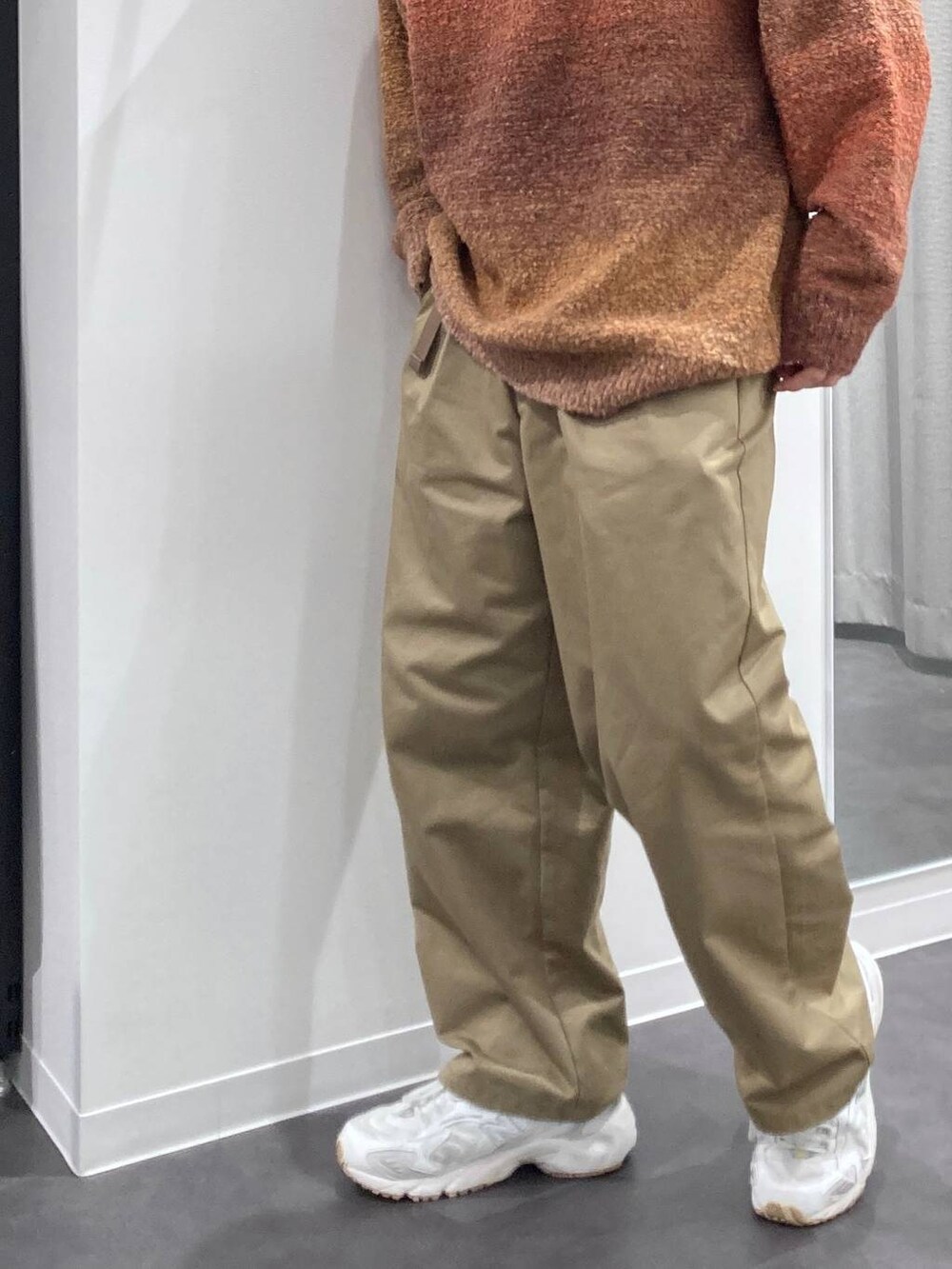 ホワイト系のスニーカー、オレンジ系のニット/セーター、ベージュ系のチノパンツを着用したメンズの秋コーディネートの7枚目の写真