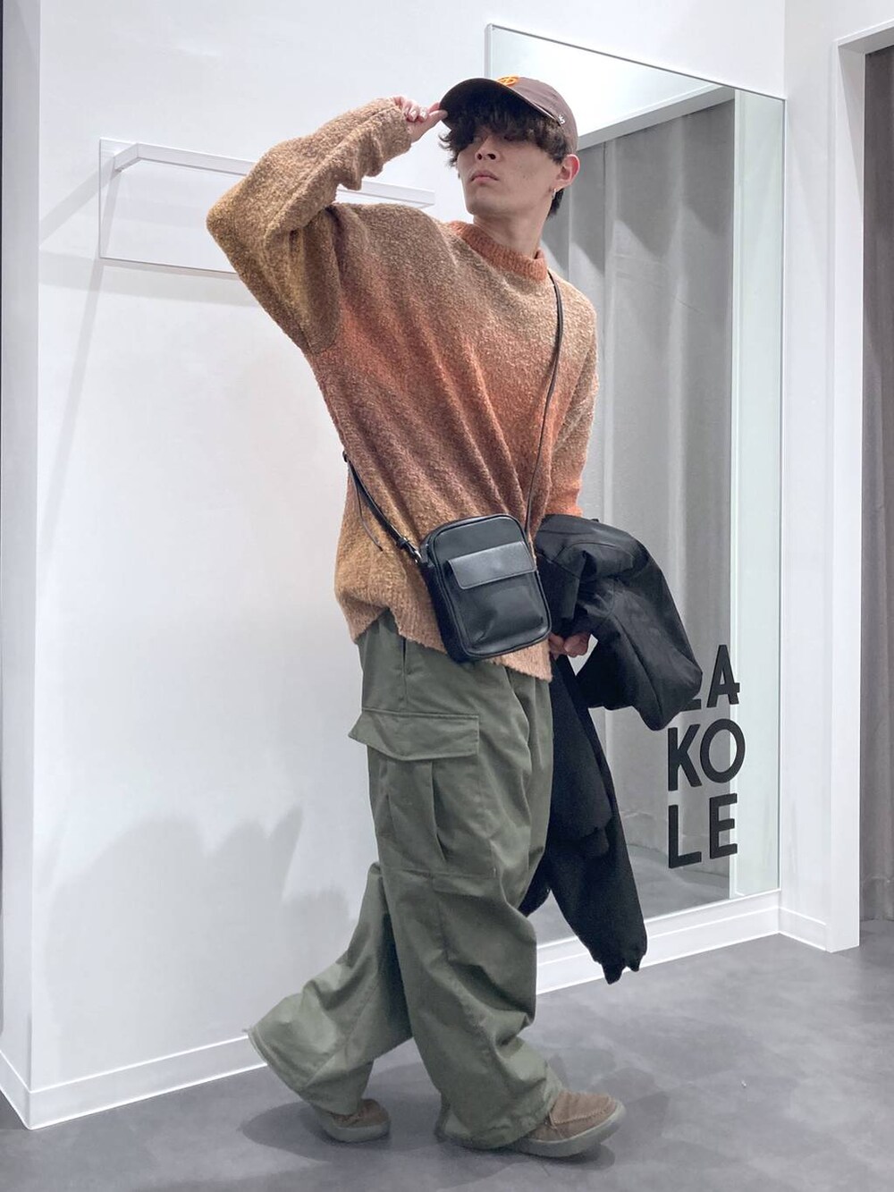 オレンジ系のニット/セーター、ブラック系のショルダーバッグ、ブラック系のブルゾンを着用したメンズの冬コーディネートの6枚目の写真