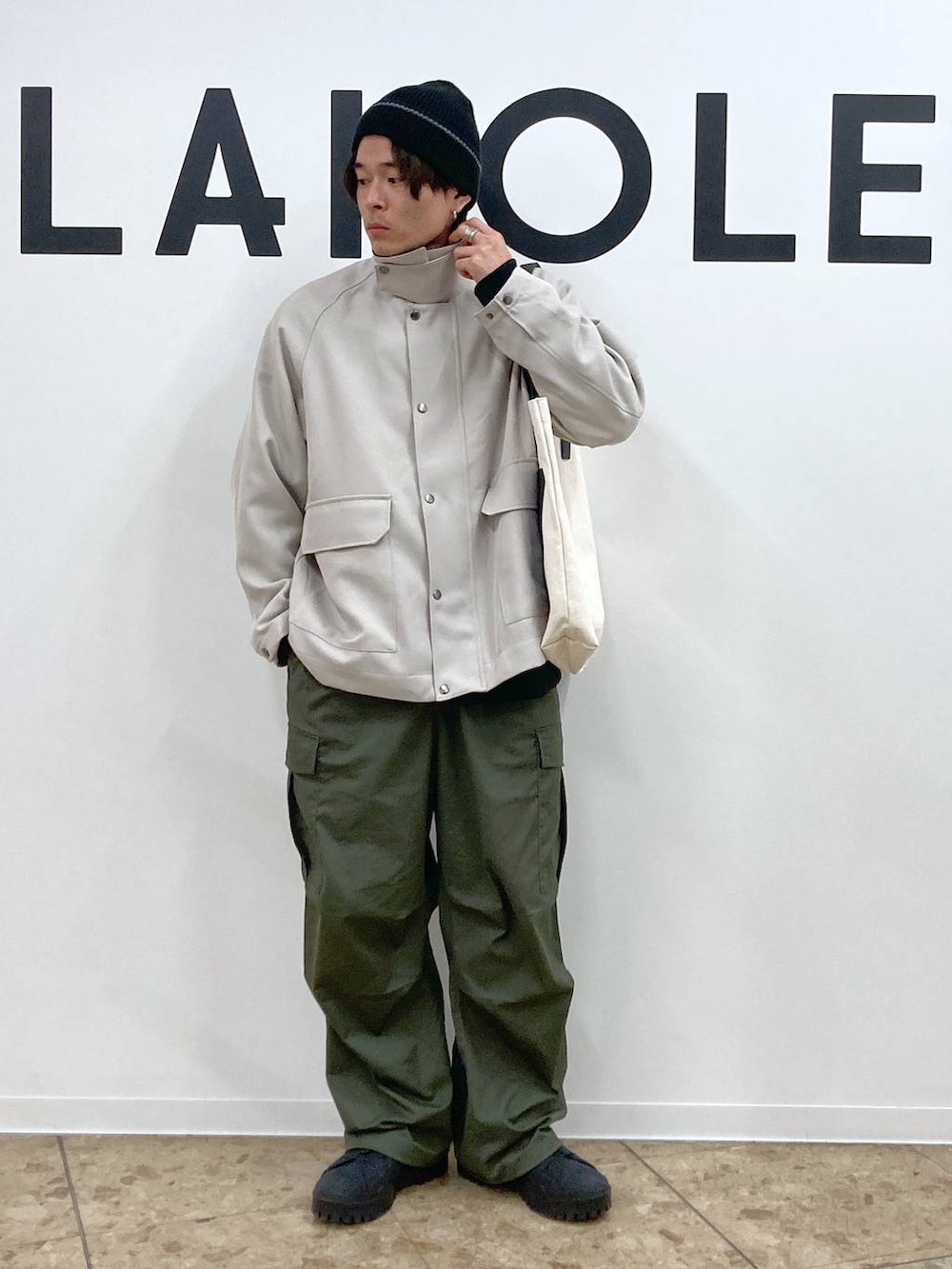 ベージュ系のトートバッグ、ブラック系のその他トップス、グリーン系のカーゴパンツを着用したメンズの冬コーディネートの9枚目の写真