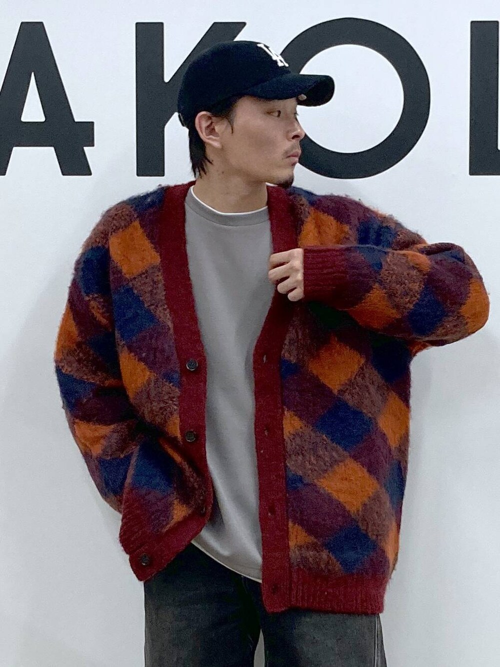オレンジ系のカーディガン/ボレロ、グレー系のTシャツ/カットソー、ブラック系のデニムパンツを着用したメンズの冬コーディネートの4枚目の写真
