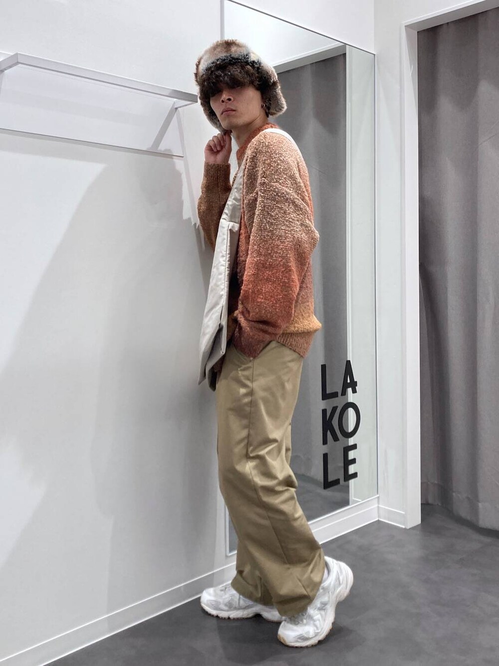 ホワイト系のスニーカー、オレンジ系のニット/セーター、ベージュ系のチノパンツを着用したメンズの秋コーディネートの3枚目の写真