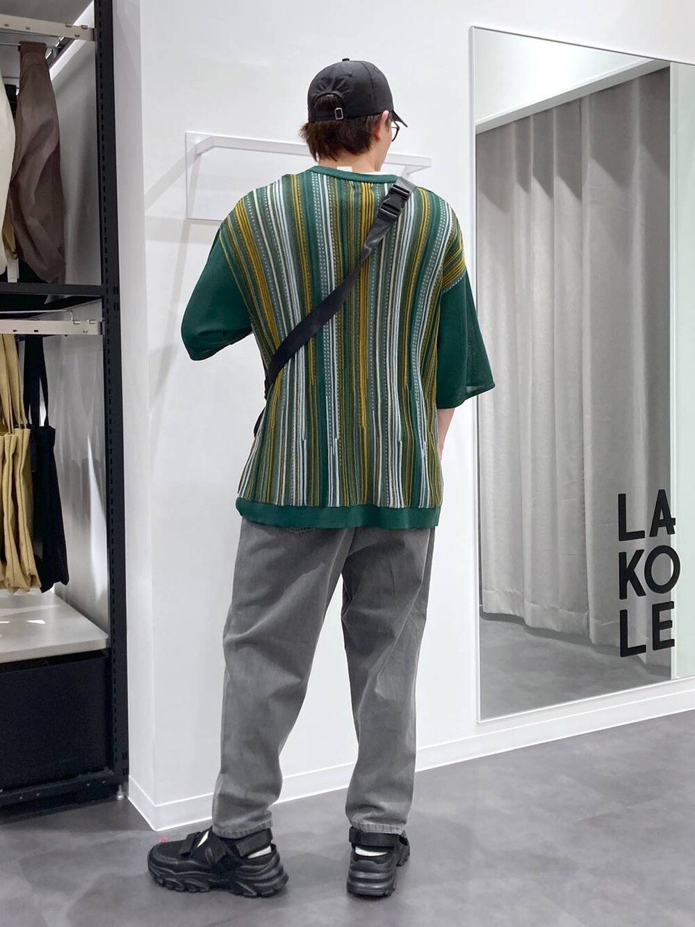 ブラック系のスニーカー、ブラック系のボディバッグ/ウエストポーチ、ホワイト系のTシャツ/カットソーを着用したメンズの夏コーディネートの2枚目の写真