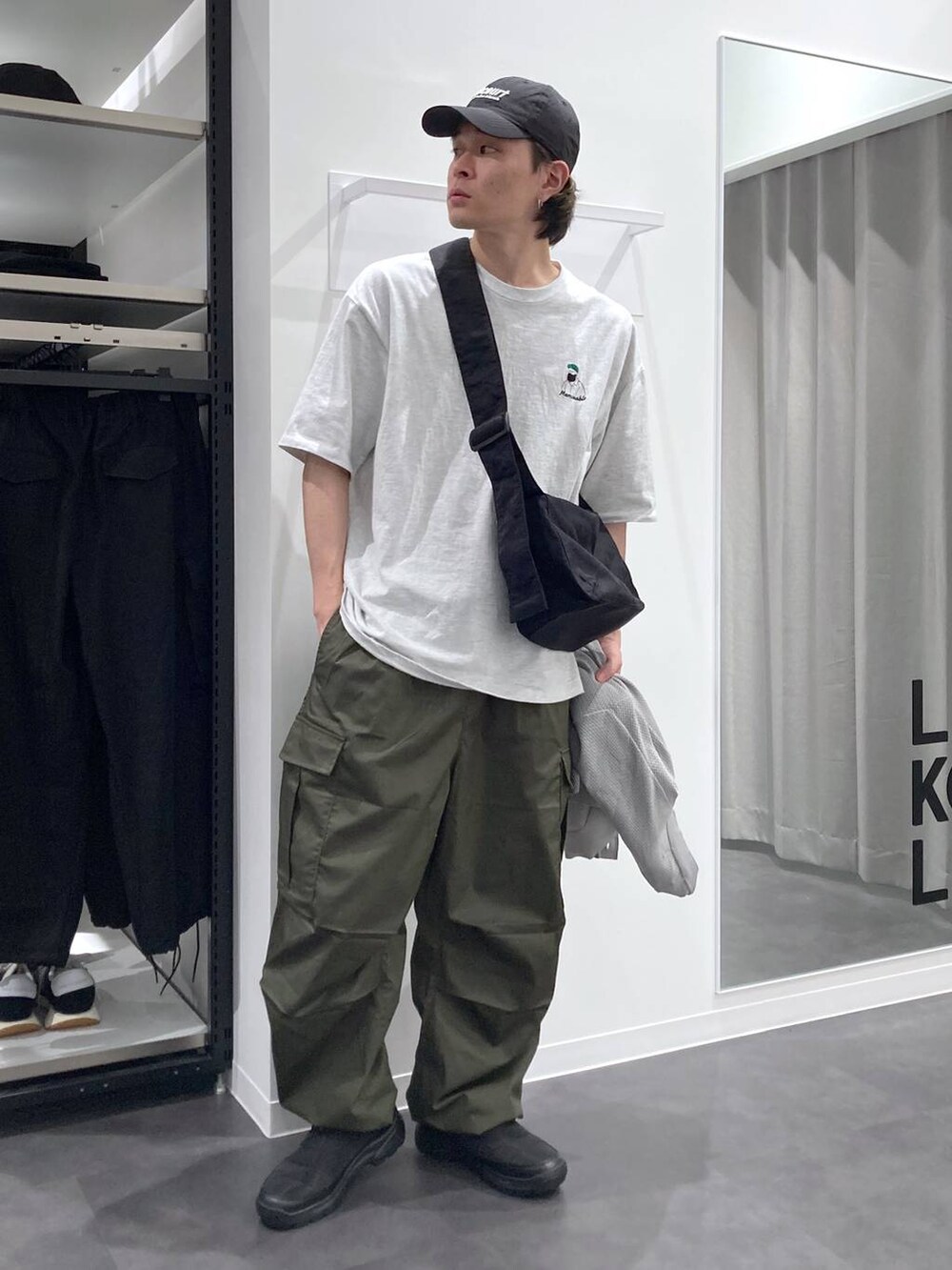 グレー系のTシャツ/カットソー、ブラック系のスリッポン、グリーン系のカーゴパンツを着用したメンズの春コーディネートの4枚目の写真