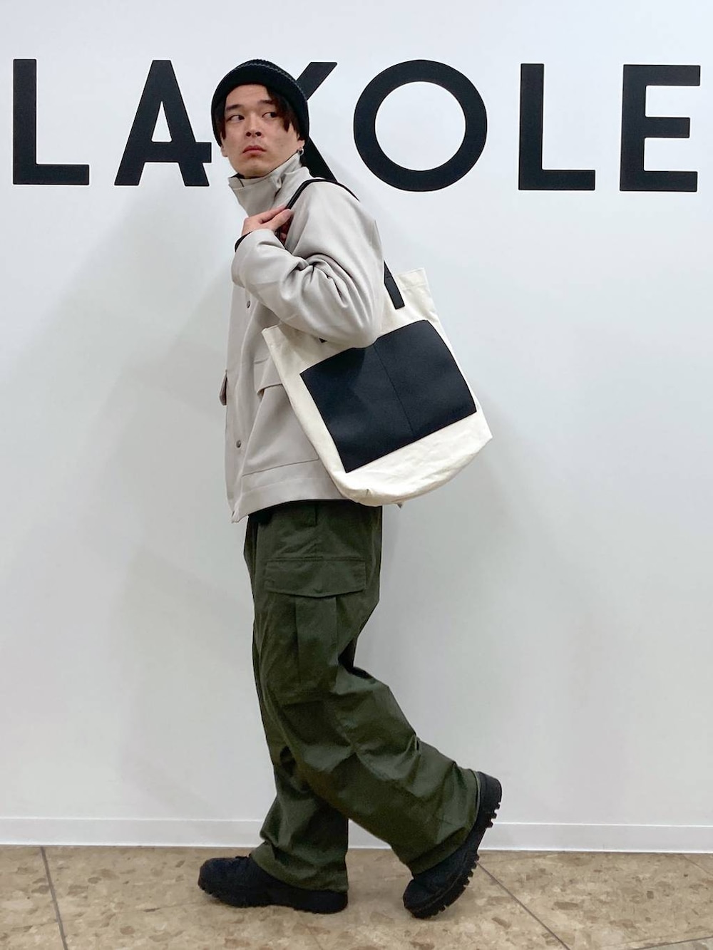 ベージュ系のトートバッグ、ブラック系のその他トップス、グリーン系のカーゴパンツを着用したメンズの冬コーディネートの3枚目の写真