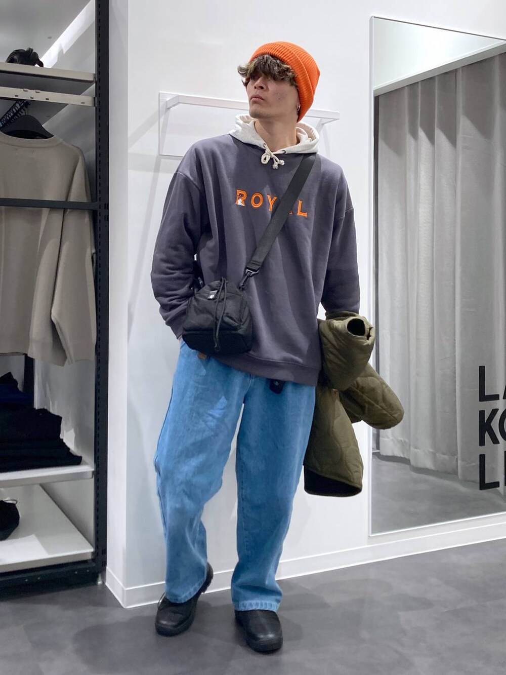 ホワイト系のパーカー、ブラック系のショルダーバッグ、グリーン系のブルゾンを着用したメンズの冬コーディネートの7枚目の写真