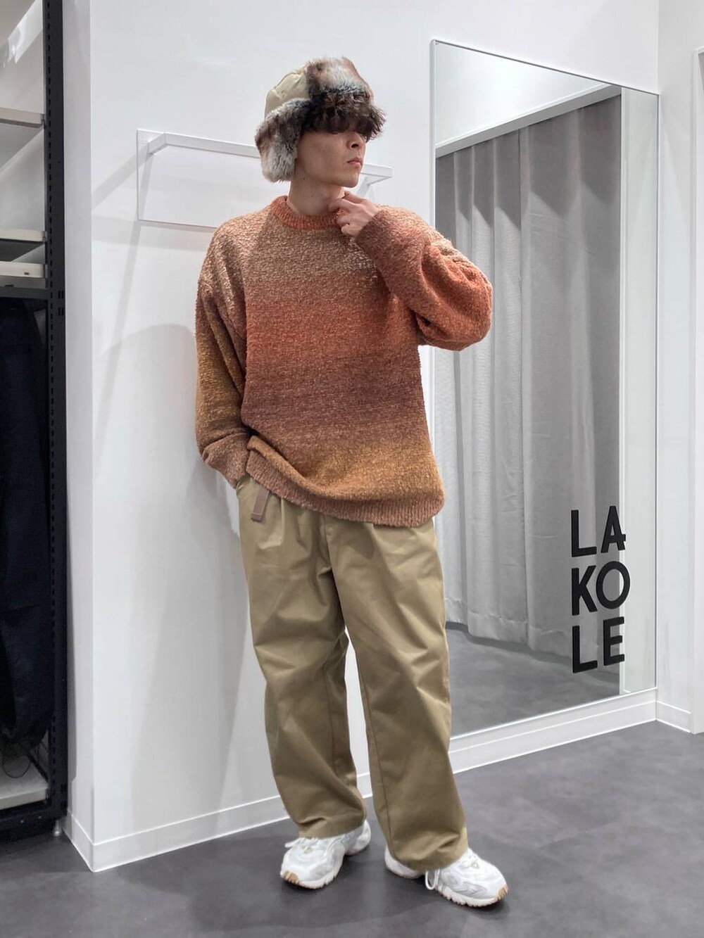 ホワイト系のスニーカー、オレンジ系のニット/セーター、ベージュ系のチノパンツを着用したメンズの秋コーディネートの6枚目の写真