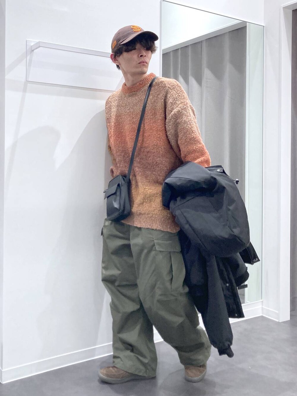 オレンジ系のニット/セーター、ブラック系のショルダーバッグ、ブラック系のブルゾンを着用したメンズの冬コーディネートの4枚目の写真