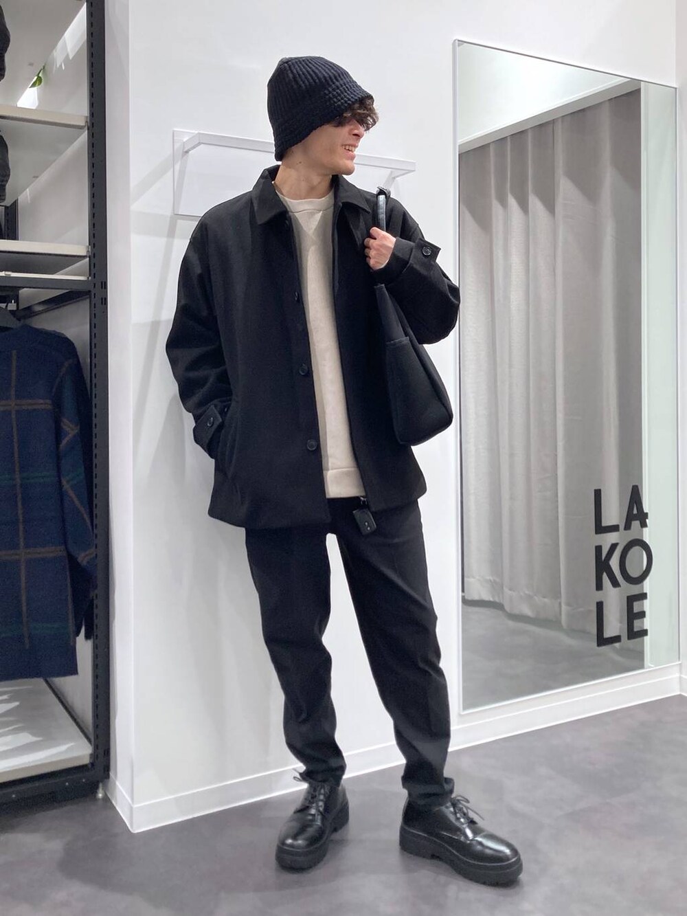 ブラック系のステンカラーコート、ブラック系のトートバッグ、ブラック系のドレスシューズを着用したメンズの冬コーディネートの6枚目の写真