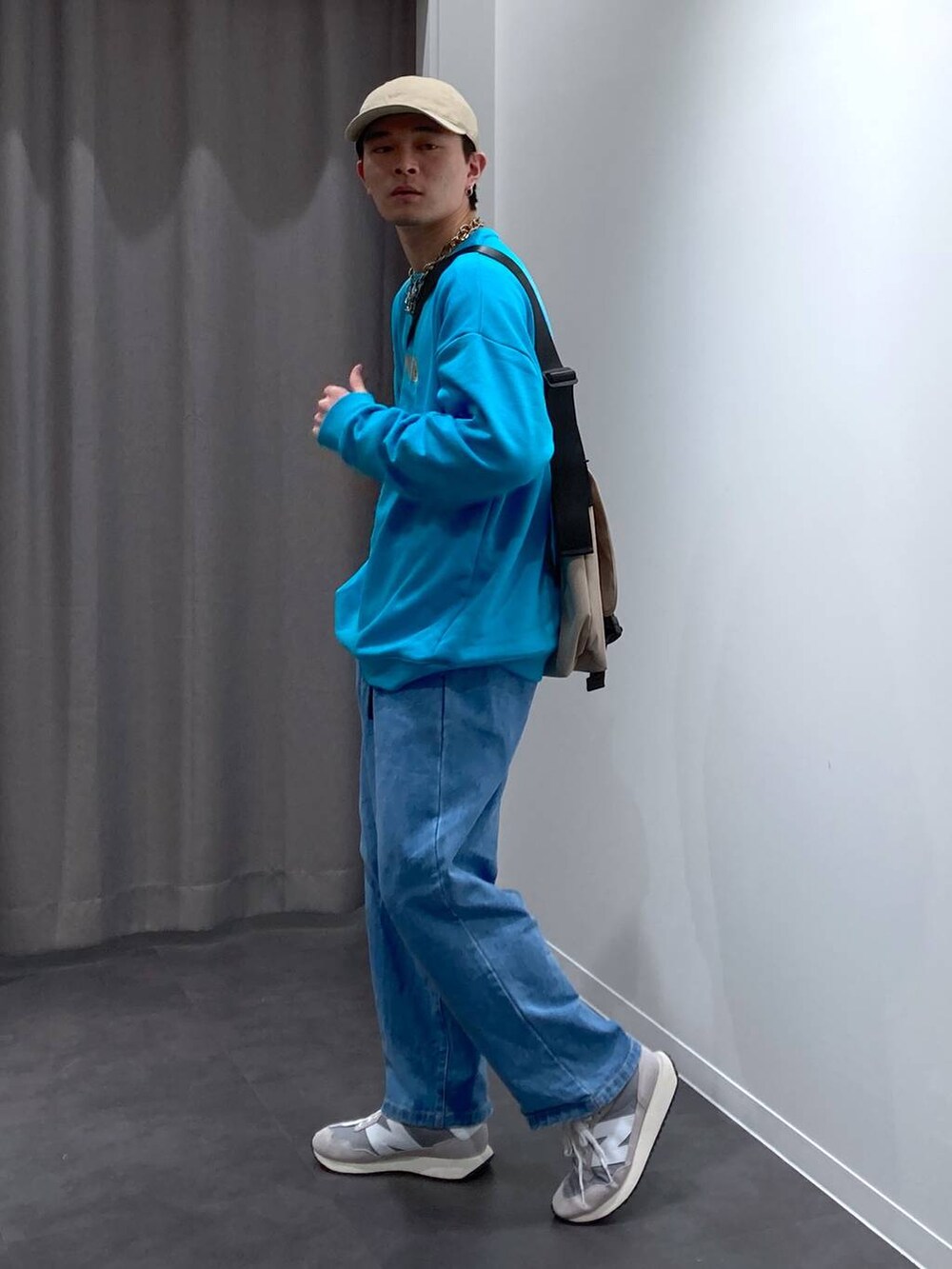 グレー系のスニーカー、ベージュ系のメッセンジャーバッグ、ブルー系のデニムパンツを着用したメンズの冬コーディネートの5枚目の写真