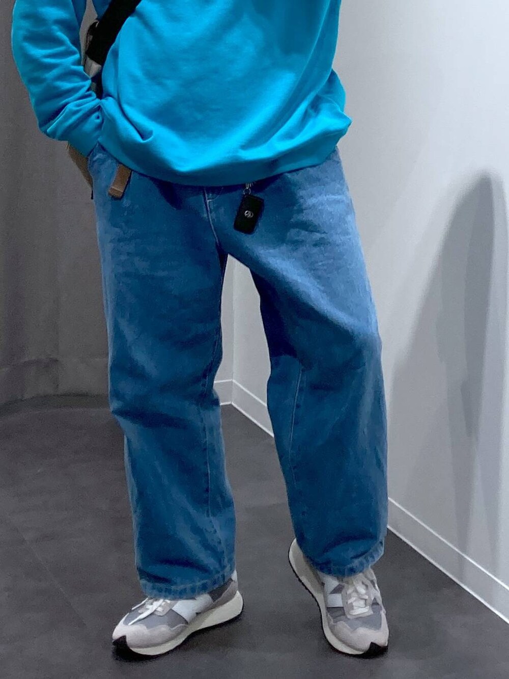 グレー系のスニーカー、ベージュ系のメッセンジャーバッグ、ブルー系のデニムパンツを着用したメンズの冬コーディネートの7枚目の写真