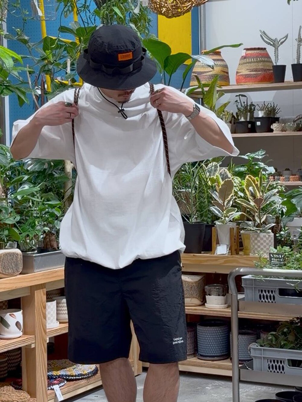 ブラック系のスニーカー、オレンジ系のバックパック/リュック、ホワイト系のTシャツ/カットソーを着用したメンズの春コーディネートの5枚目の写真