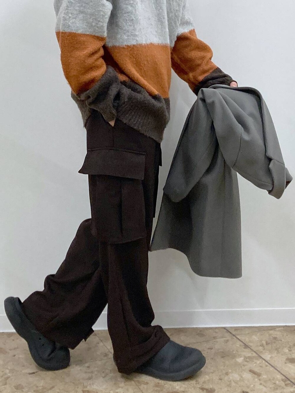 グレー系のチェスターコート、ブラウン系のカーゴパンツ、ブラウン系のニット/セーターを着用したメンズの冬コーディネートの9枚目の写真