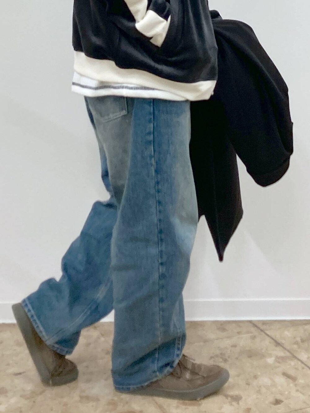 ブラック系のチェスターコート、ブルー系のデニムパンツ、ホワイト系のTシャツ/カットソーを着用したメンズの秋コーディネートの9枚目の写真