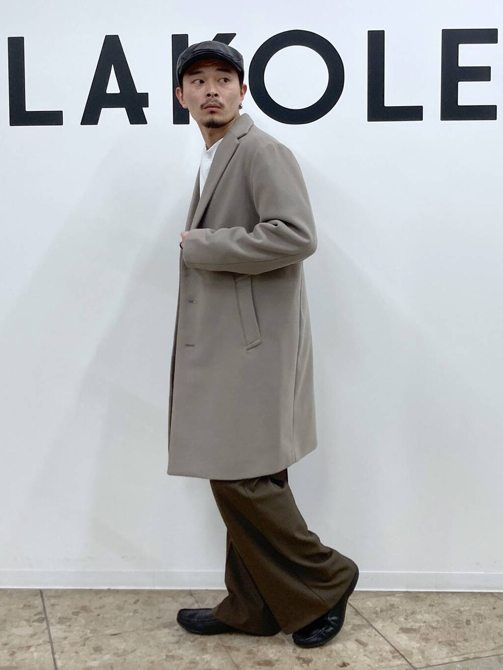 ホワイト系のチェスターコート、ブラウン系のその他パンツ、ブラック系のハンチング/ベレー帽を着用したメンズの秋コーディネートの3枚目の写真