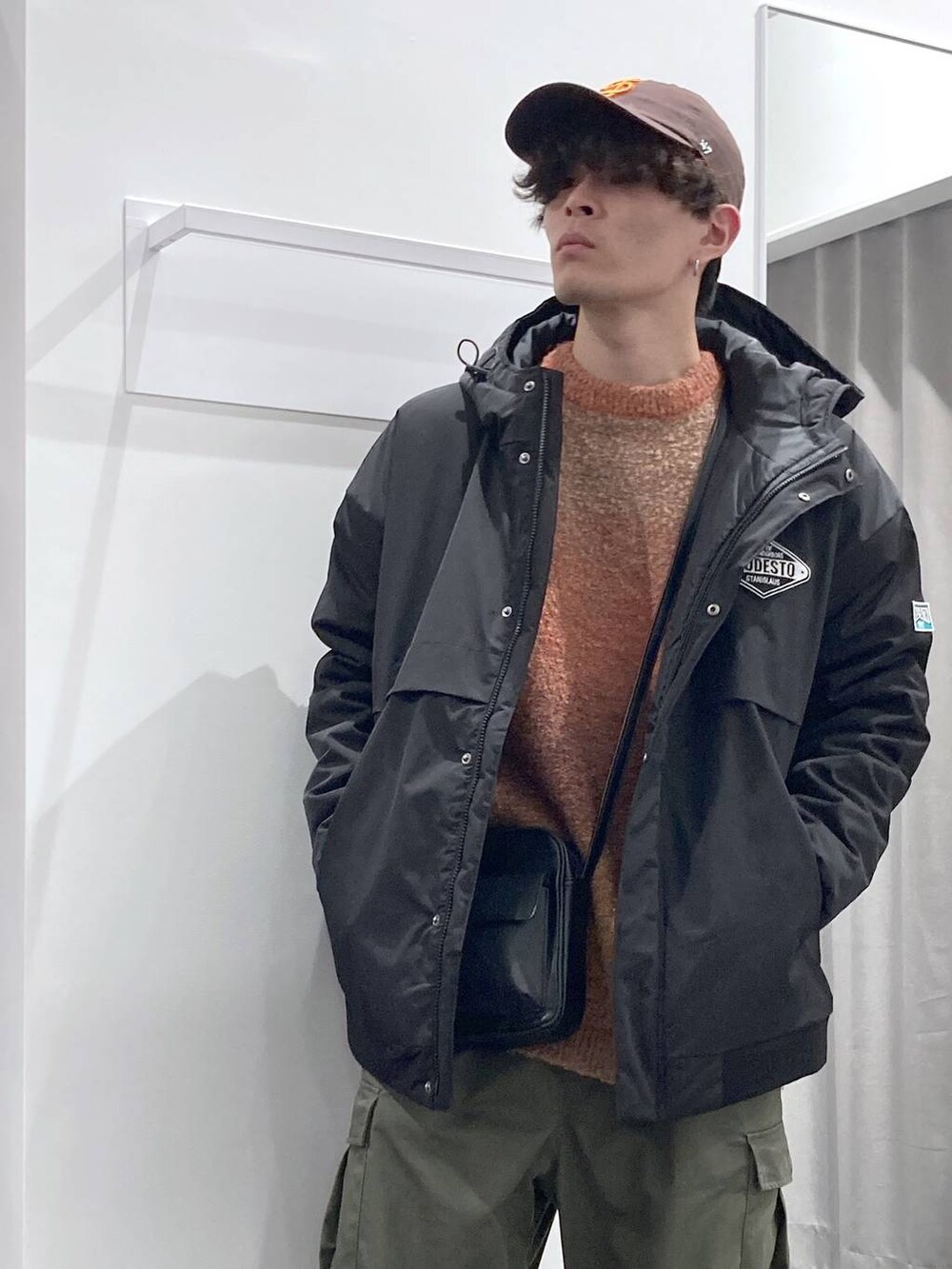 オレンジ系のニット/セーター、ブラック系のショルダーバッグ、ブラック系のブルゾンを着用したメンズの冬コーディネートの7枚目の写真