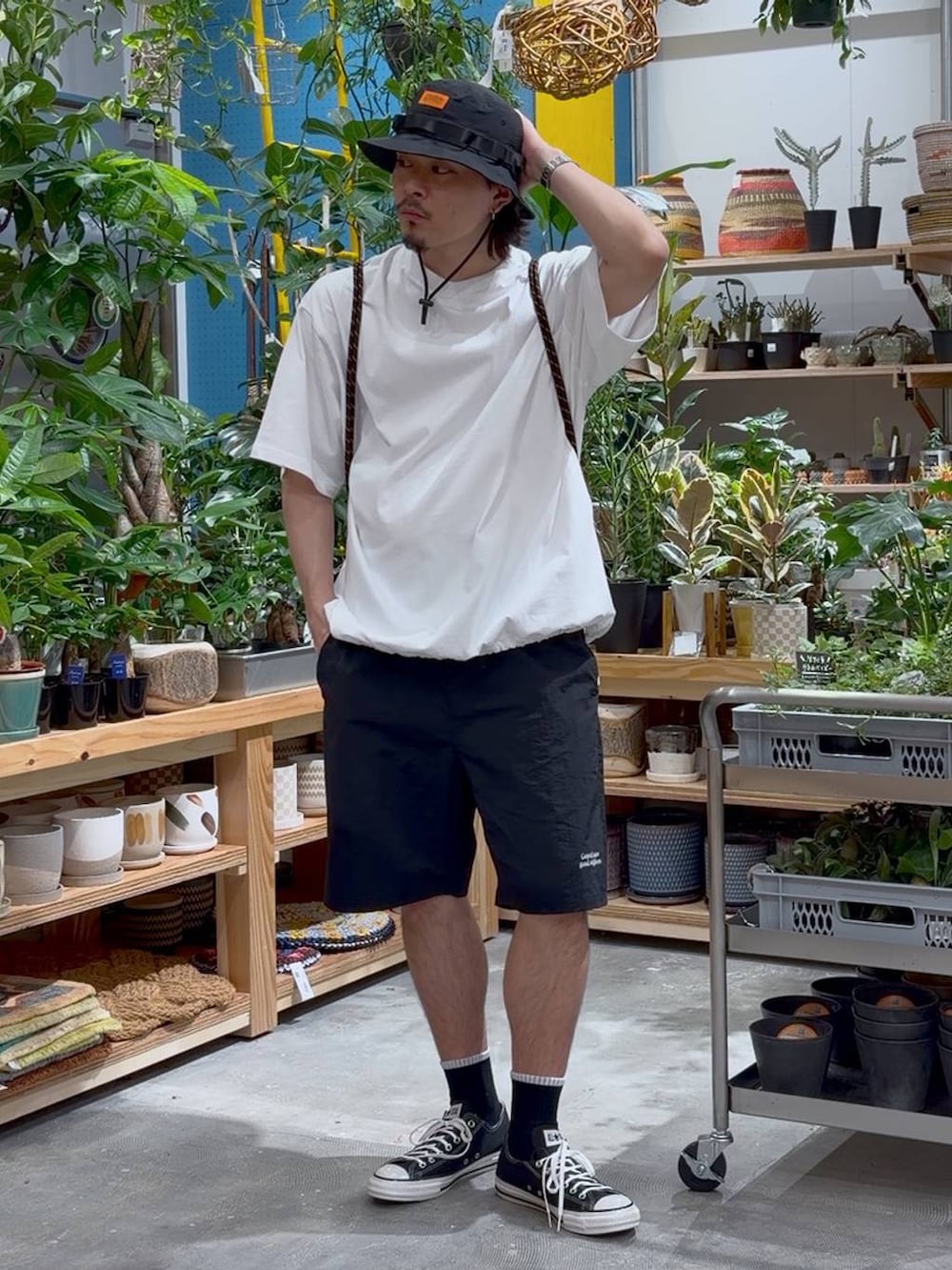 ブラック系のスニーカー、オレンジ系のバックパック/リュック、ホワイト系のTシャツ/カットソーを着用したメンズの春コーディネートの3枚目の写真