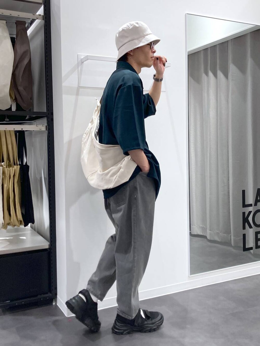 ブラック系のスニーカー、ベージュ系のショルダーバッグ、グリーン系のシャツ/ブラウスを着用したメンズの夏コーディネートの4枚目の写真