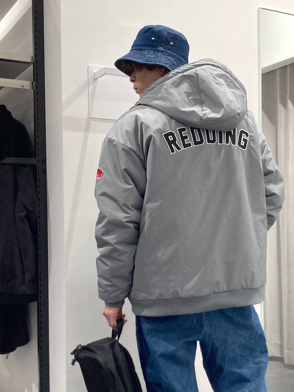 ブラック系のバックパック/リュック、ブルー系のシャツ/ブラウス、ベージュ系のニット/セーターを着用したメンズの冬コーディネートの2枚目の写真