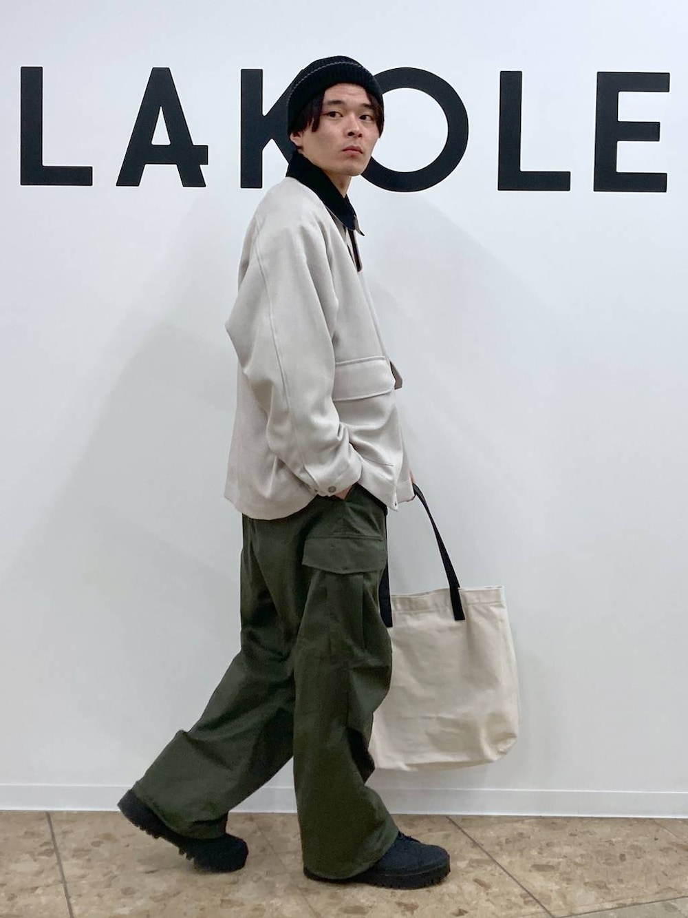 ベージュ系のトートバッグ、ブラック系のその他トップス、グリーン系のカーゴパンツを着用したメンズの冬コーディネートの4枚目の写真