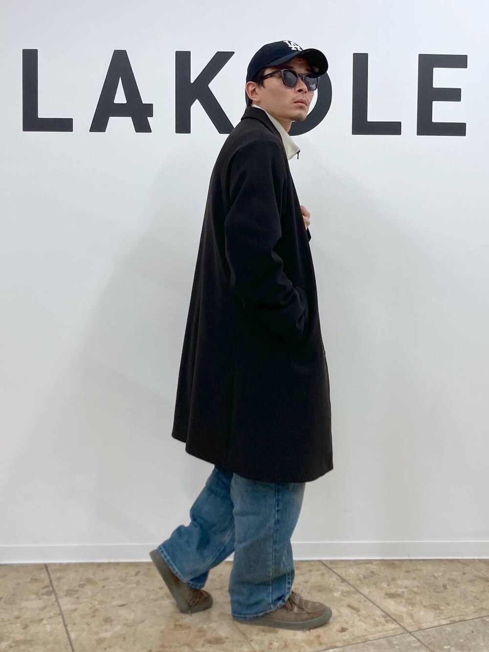 ブラック系のチェスターコート、ブルー系のデニムパンツ、ホワイト系のTシャツ/カットソーを着用したメンズの秋コーディネートの3枚目の写真