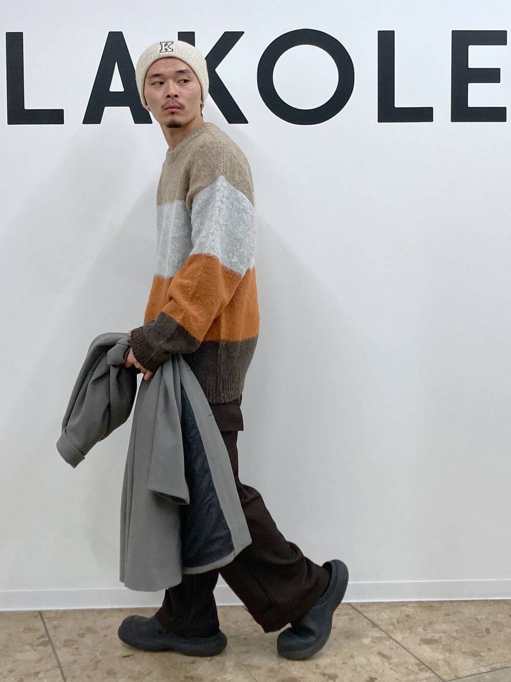 グレー系のチェスターコート、ブラウン系のカーゴパンツ、ブラウン系のニット/セーターを着用したメンズの冬コーディネートの7枚目の写真