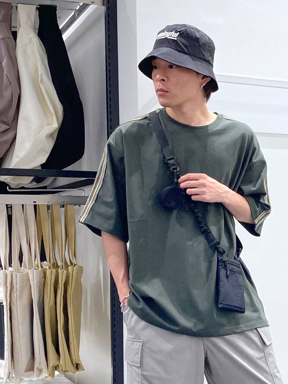 ブラック系のショルダーバッグ、ブラック系のサンダル、グリーン系のTシャツ/カットソーを着用したメンズの夏コーディネートの6枚目の写真