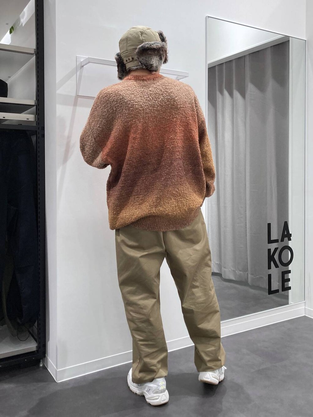 ホワイト系のスニーカー、オレンジ系のニット/セーター、ベージュ系のチノパンツを着用したメンズの秋コーディネートの2枚目の写真