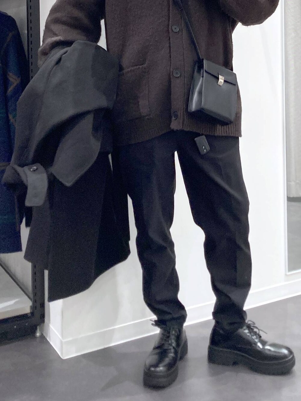 ブラック系のトレンチコート、グレー系のTシャツ/カットソー、ホワイト系のスウェットを着用したメンズの冬コーディネートの9枚目の写真